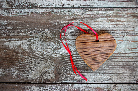 Wooden heart with red ribbon on a wooden table