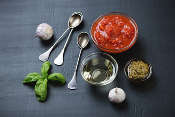 Still life with chopped tomatoes, olive oil, pesto and garlic