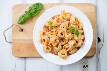 Glass plate with tortellini in tomato sauce, above view
