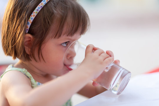 Little girl drinking water outdoors