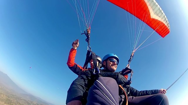 paragliding high above valley at bright blue sky