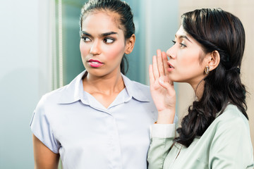 Gossip in the office, woman whispering in ear