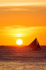 Fototapeta na wymiar Sailboats at sunset on a tropical sea. Silhouette photo.