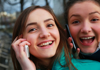 Girls with a mobile phones having fun outside.