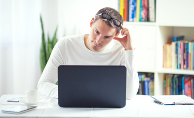 Tired young businessman working at home