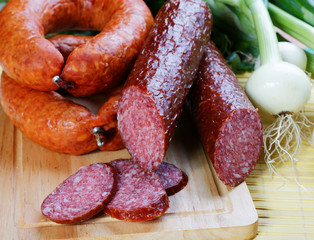 Still-life with smoked sausage and an onions on a kitchen table