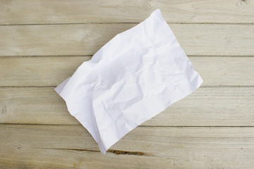 Wrinkled sheet of white paper on wood