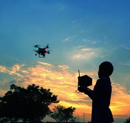 silhouette boy play drone / quadcopter  during sunrise or sunset