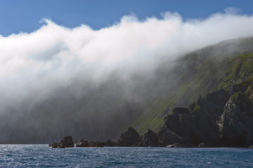 Rocky coastline, covered with a cloud of mist.