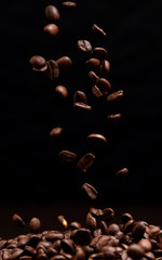 High contrast image of coffee beans being dropped onto pile with