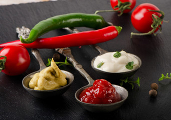 Mustard, ketchup and mayonnaise on a  black table.