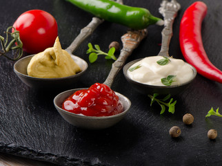 Mustard, tomato sauce and mayonnaise on  a  table.