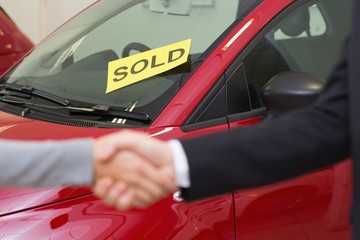 Naklejka premium Person shaking hands in front of a sold car