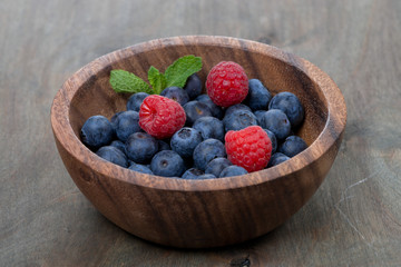 blueberries and raspberries in wooden bowl
