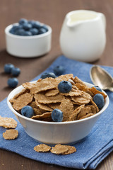 wholegrain flakes with blueberries and jug of milk, vertical