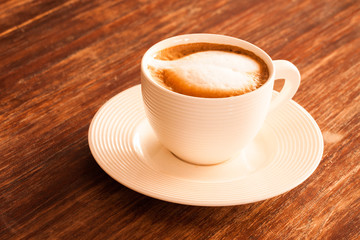 A cup of hot latte  coffee  on a wooden table.