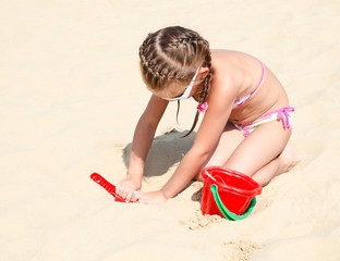 Cute smiling little girl playing on beach