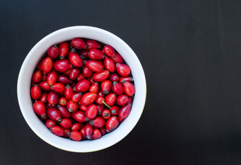 Closeup of rose-hip berries in white bow with black background