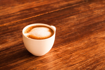 A cup of hot latte  coffee  on a wooden table.