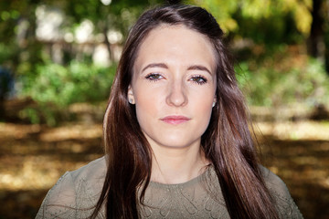 Woman with long hair in front of colorful trees in autumn
