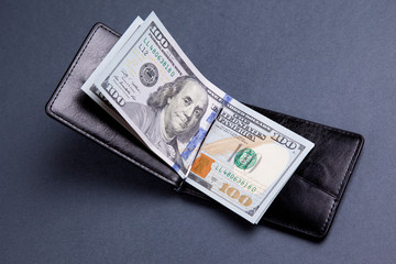 purse with hundred dollar banknotes on grey background