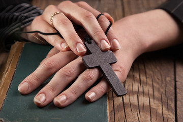 closeup of hands holding vintage cross on Bible