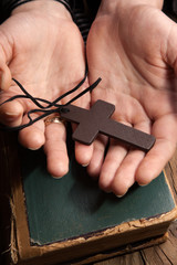 Obraz na płótnie Canvas closeup of hands holding vintage cross on Bible