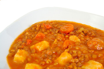 Brown cooked lentils with sausage, carrot and potato.