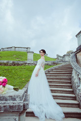 Beautiful woman in vintage wedding dress stay on stairs