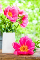 Pink peony and empty card for letter on table in garden