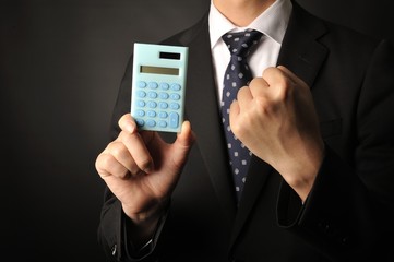 水色のデジタル計算機を手にしているスーツのビジネスマン男性