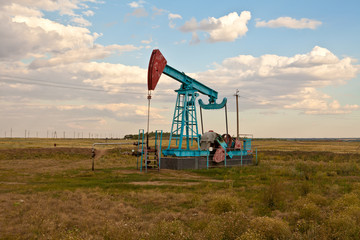 Oil pump in the field on a background cloudy sky