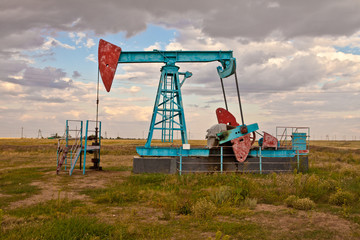 Oil pump in the field on a background cloudy sky