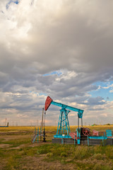 Fototapeta na wymiar Oil pump in the field on a background cloudy sky