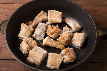Some pieces of fried fish filet in a frying pan