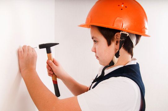 boy hammer a nail into the wall