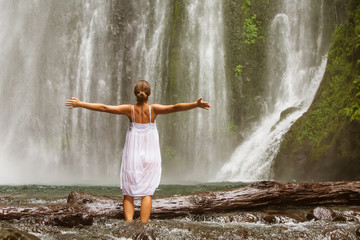 young woman doing yoga in a forest near waterfall