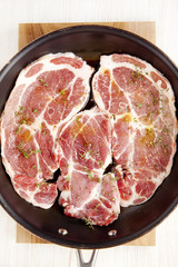 raw beefsteak with seasoning & olive oil in pan. wooden bord. on