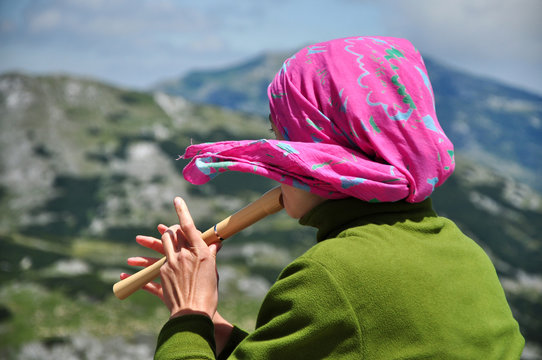 Girl playing on flute in the mountains