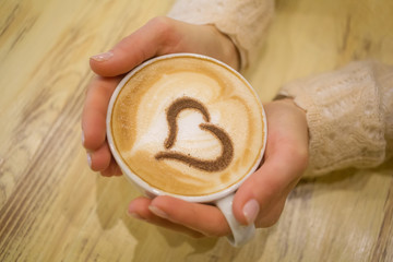woman holding hot cup of coffee, with heart shape
