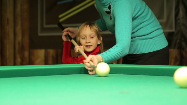 Little girl with  mom plays billiards