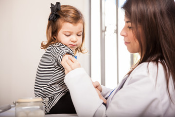 Pediatrician rubbing alcohol on a girl's arm