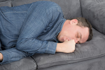 Homme qui suce son pouce sur le canapé