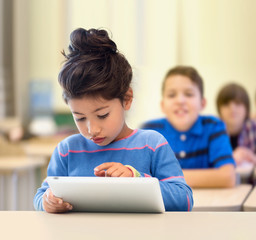 little school girl with tablet pc over classroom