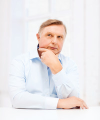 stressed old man holding head at home