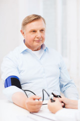 female doctor or nurse measuring blood pressure