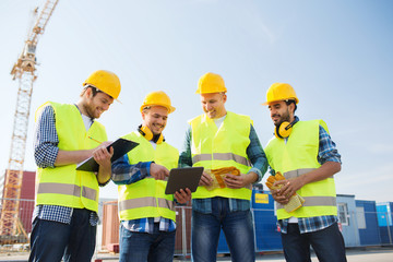 group of smiling builders with tablet pc outdoors
