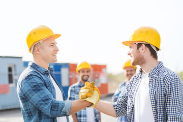 group of smiling builders in hardhats outdoors