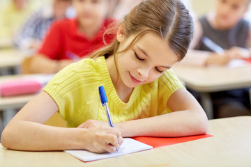 group of school kids writing test in classroom