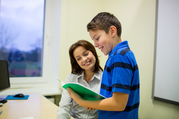 school boy with notebook and teacher in classroom
